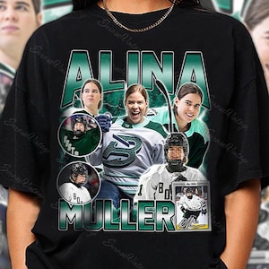 Könnte beinhalten: Schwarzes T-Shirt mit einer Grafik der Eishockeyspielerin Alina Muller. Das Design enthält den Namen "ALINA MULLER" in grünen Blockbuchstaben sowie Bilder der Spielerin in Aktion. Das T-Shirt hat einen Vintage-Stil.