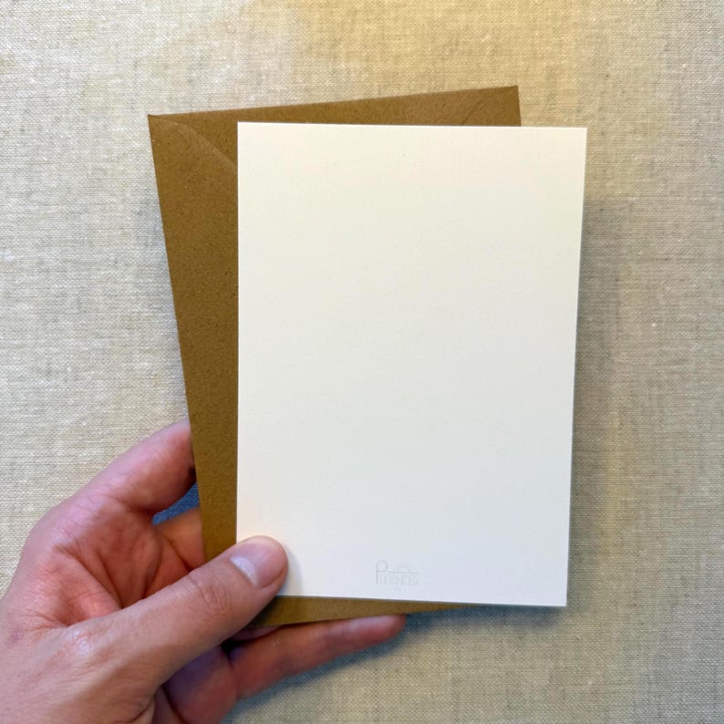 May include: A white card with a small logo in the bottom right corner is held in front of a brown envelope. The card and envelope are set against a neutral, textured background.