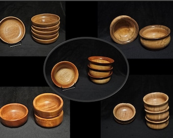May include: A collection of wooden bowls in various sizes and styles. The bowls are made of light brown wood with a natural grain pattern. Some of the bowls are stacked on top of each other, while others are displayed individually.
