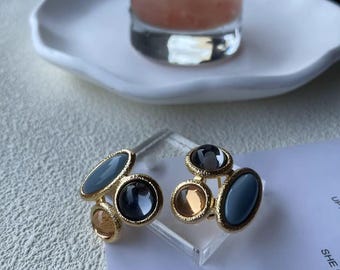 May include: A pair of gold-tone earrings with blue and orange glass stones. The earrings are in the shape of a cluster of stones.