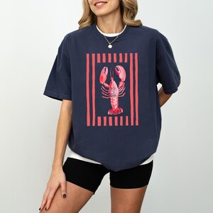 Navy t-shirt with red lobster graphic and vertical stripes.