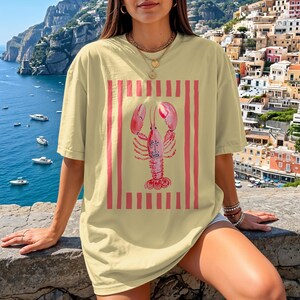 Yellow t-shirt with a pink lobster and red stripes design.