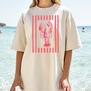 Cream t-shirt with a pink lobster design and vertical stripes.