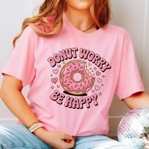 May include: Pink t-shirt with a donut graphic and the text "Donut Worry Be Happy".