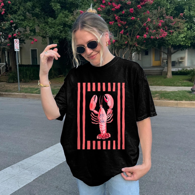 Black t-shirt with a pink lobster graphic and vertical stripes.