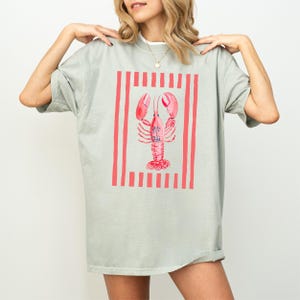 Pale green t-shirt with a coral pink lobster graphic and vertical stripes.