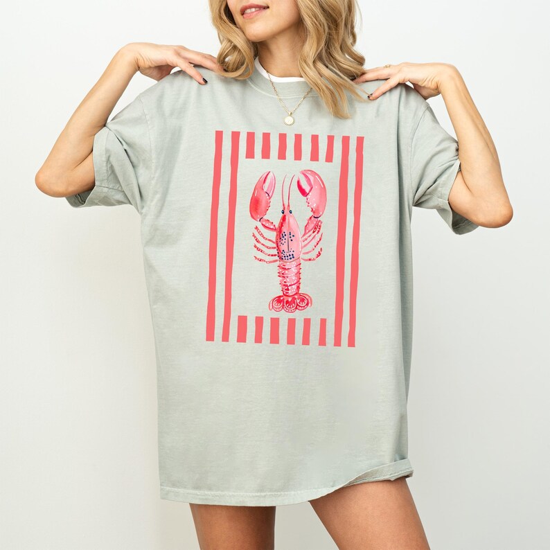 Pale green t-shirt with a coral pink lobster graphic and vertical stripes.