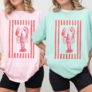 Pink and mint t-shirts with lobster and stripes graphic.