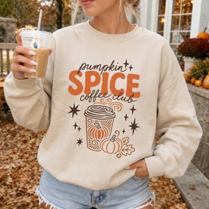 Cream sweatshirt with orange "Pumpkin Spice Coffee Club" graphic and coffee cup.