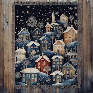 Könnte beinhalten: Eine gewebte Tagesdecke mit einer Winterdorf-Szene. Das Design zeigt Häuser mit schneebedeckten Dächern vor einem dunkelblauen Nachthimmel mit Sternen und einem Halbmond. Die Decke hat einen Fransenrand.