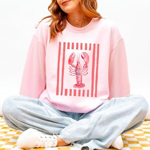 Pink sweatshirt with a lobster graphic and red and white stripes.