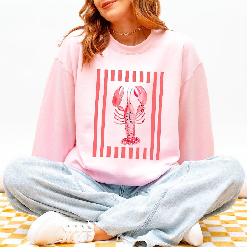 Pink sweatshirt with a lobster graphic and red and white stripes.