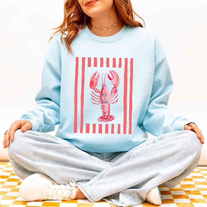 Light blue sweatshirt with a pink lobster graphic and red stripes.