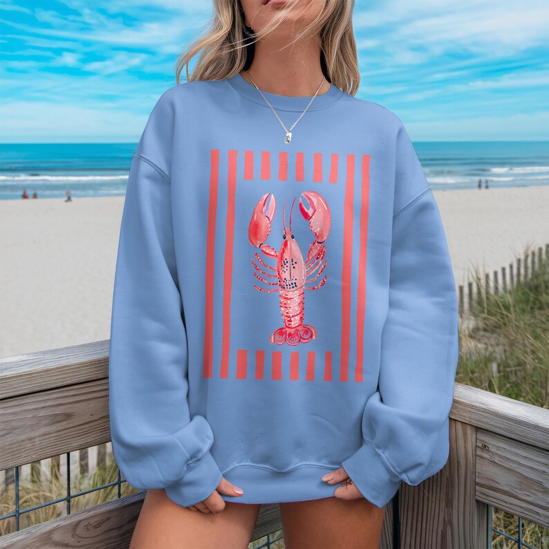 Light blue sweatshirt with coral lobster and stripes graphic.