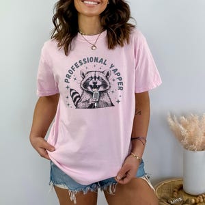 a woman wearing a pink shirt with a raccoon on it