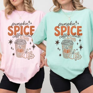 Two women wear graphic tees with pumpkin spice coffee club design.
