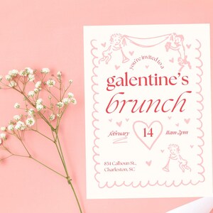 May include: A pink and white invitation card with a pink border and a heart-shaped design. The text on the card reads "You're invited to a Galentine's Brunch" with the date "February 14" and the time "11am-2pm". The address is "834 Calhoun St., Charleston, SC".