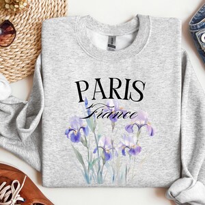 May include: Gray sweatshirt with a graphic print of purple iris flowers and the text "PARIS France".