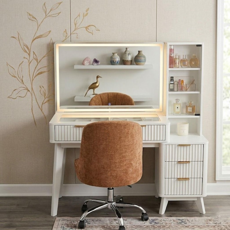 May include: A white vanity desk with a rectangular LED-lit mirror, a glass-top drawer, and a side cabinet with three drawers featuring gold handles. A brown upholstered swivel chair with a chrome base is positioned in front of the desk.