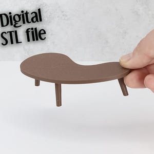 Könnte beinhalten: Ein kleiner, brauner Tisch mit drei Beinen und einer geschwungenen Oberseite. Der Text "Digital STL file" befindet sich in der oberen linken Ecke. Der Tisch wird von einer Hand vor einem weißen und grauen Hintergrund gehalten.