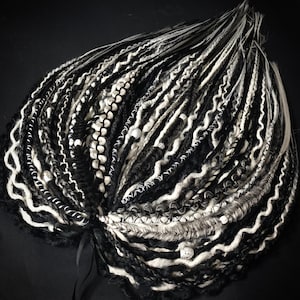 May include: Black and white synthetic dreadlocks with white beads. The dreadlocks are long and wavy.
