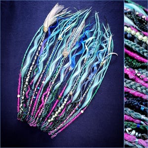 May include: A collection of teal, blue, and pink dreadlocks with decorative feathers, shells, and beads. The dreadlocks are arranged in a fan shape against a dark blue background. Braided and twisted strands create a unique hair accessory.