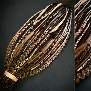May include: A bundle of brown, blonde, and pink synthetic dreadlocks. The dreadlocks are adorned with white ribbons, small beads, and decorative accents. The base of the dreadlocks is secured with a peach-colored ribbon.