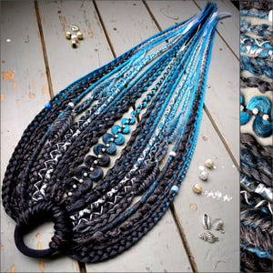 May include: Braided dreadlocks in shades of blue and gray, with white and turquoise accents. The dreads are adorned with decorative beads and a black hair tie. A stylish hair accessory.