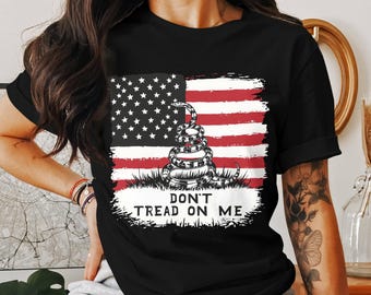 May include: Black t-shirt featuring a graphic of a coiled snake in front of an American flag. The text "Don't Tread On Me" is printed below the snake.