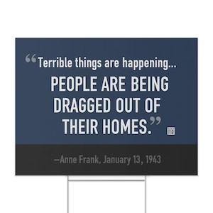 Pode incluir: Uma placa de jardim azul escuro com texto branco citando Anne Frank: "Coisas terríveis estão acontecendo... AS PESSOAS ESTÃO SENDO ARRASTADAS PARA FORA DE SUAS CASAS". A citação é de 13 de janeiro de 1943.