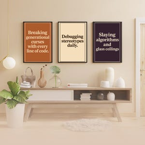 May include: Three framed prints with motivational quotes for women in tech. The first print has a brown background and says "Breaking generational curses with every line of code." The second print has a cream background and says "Debugging stereotypes daily." The third print has a black background and says "Slaying algorithms and glass ceilings."