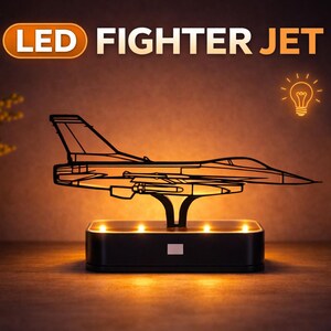 Puede incluir: Una lámpara LED de avión de combate. La lámpara presenta un contorno negro de un avión de combate, iluminado por luces de tonos cálidos. La base es una caja negra rectangular con luces adicionales. Las palabras "LED FIGHTER JET" se muestran encima del avión.