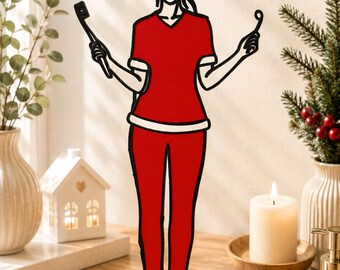 May include: A flat, stylised metal cutout figure wearing a red V-neck top, red trousers, and a red Santa hat with white trim. The figure holds a black toothbrush in one hand and a dental mirror in the other, standing on a black base labelled NAME.