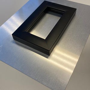 May include: A metal print with a black frame. The print is on a silver background. The text "METAL PRINTS" is printed on the bottom of the image.
