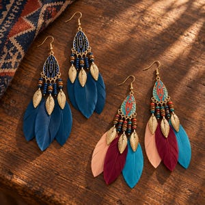 May include: Two pairs of long dangle earrings featuring gold-tone teardrop charms with geometric enamel patterns, small metallic leaf accents, and rows of colorful beads. One pair has dark blue feathers, while the other has peach, maroon, and teal feathers.