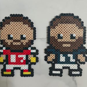 May include: Two pixel art figures, likely representing athletes, are depicted. One wears a red jersey with the number 83, the other a navy blue jersey with the number 87. Both figures have brown hair and beards.