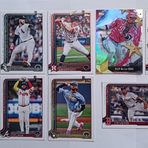 May include: A collection of baseball trading cards featuring various players in action poses. The cards have a white border and include team logos and player names. Some cards have a holographic finish, adding a visual appeal to the collection.