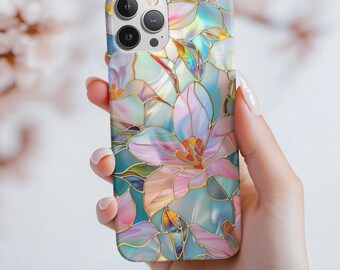 Può includere: Una custodia per telefono floreale con un design a vetrata. La custodia ha una finitura perlata con un motivo di fiori e foglie rosa, blu e oro. La custodia ha un ritaglio per la fotocamera ed è tenuta in mano.