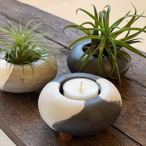 May include: Three ceramic planters with a black and white yin yang design. Two planters feature air plants and one planter has a small white candle in the center.