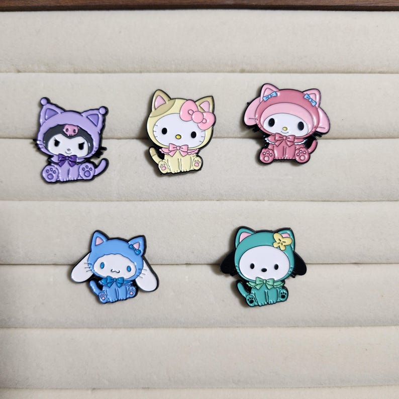 May include: Five enamel pins featuring cartoon characters dressed in costumes. The characters are a purple cat, a yellow cat, a pink rabbit, a blue dog, and a green dog. Each pin has a different costume and a different color scheme.