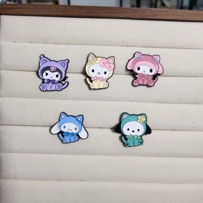 May include: Five enamel pins featuring different cartoon characters wearing various animal costumes. The characters are all wearing different colored outfits, including purple, pink, yellow, blue, and green.