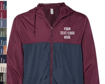 May include: A maroon and navy blue windbreaker jacket with a zipper closure and a hood. The jacket has a contrasting color design with the top half being maroon and the bottom half being navy blue. The jacket has a pocket on the left side and the text "YOUR TEXT/LOGO HERE" is printed on the right side of the jacket.