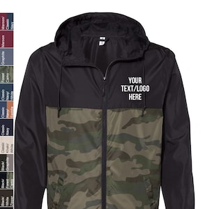 May include: A black and camouflage windbreaker jacket with a zipper closure and a hood. The jacket has a pocket on the left side and the text "YOUR TEXT/LOGO HERE" is printed on the right side of the jacket.