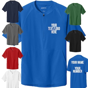 May include: A blue, short-sleeved, zippered jacket with a mock neck. The jacket has a white logo that says "YOUR TEXT/LOGO HERE". There are several other jackets in different colors in the background.