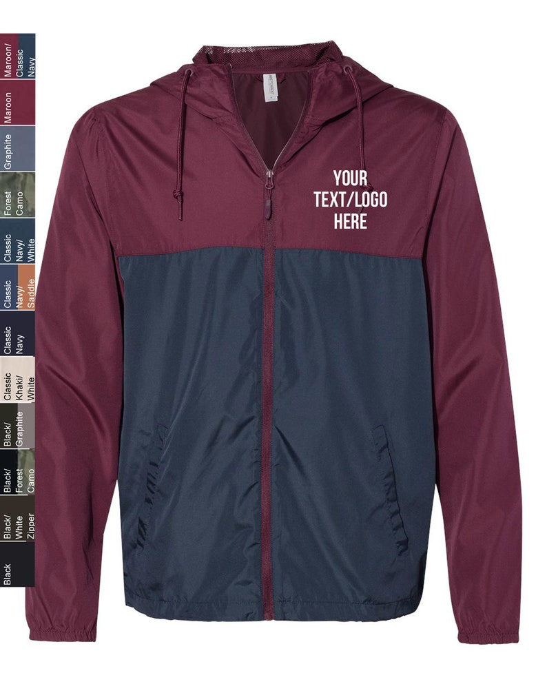 May include: A maroon and navy blue windbreaker jacket with a zip closure and a hood. The jacket has a contrasting colour design with the top half being maroon and the bottom half being navy blue. The jacket has a pocket on the left side and the text "YOUR TEXT/LOGO HERE" is printed on the right side of the jacket.