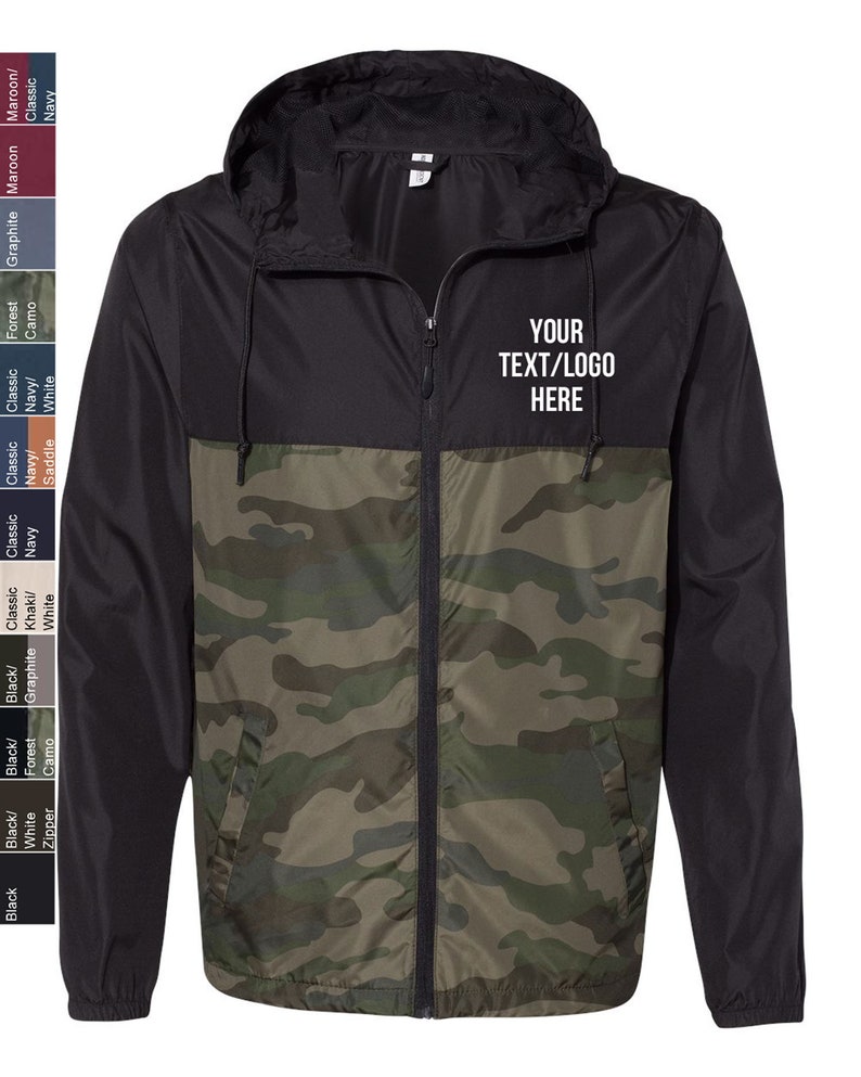 May include: A black and camouflage windbreaker jacket with a zipper closure and a hood. The jacket has a pocket on the left side and the text "YOUR TEXT/LOGO HERE" is printed on the right side of the jacket.