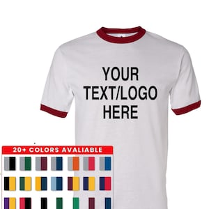 May include: A white ringer t-shirt with dark red trim on the collar and sleeve cuffs. The center of the chest features the black text YOUR TEXT/LOGO HERE. Below the shirt is a rectangular chart displaying 20+ color combinations available.