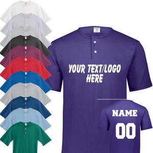 May include: A collection of short-sleeved Henley shirts in various colors, including white, gray, black, burgundy, red, blue, and green. One purple shirt displays the text "YOUR TEXT/LOGO HERE" on the front and "NAME 00" on the back.