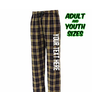 May include: Black and yellow plaid pajama pants with the text "YOUR TEXT HERE" on the right leg. Adult and youth sizes are available.