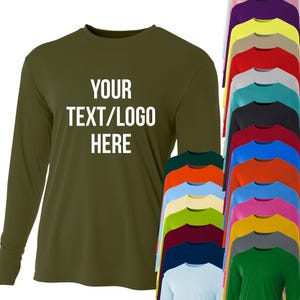 May include: An olive green long-sleeve shirt with the text "YOUR TEXT/LOGO HERE" in white. A variety of long-sleeve shirts in different colors are displayed, including white, pink, purple, yellow, and green.